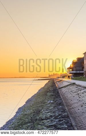 Yellow And Orange Sunset Colors Over The Dike In Wilhelmshaven, Germany