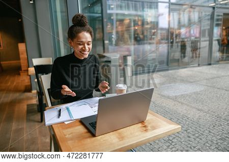 Woman Freelance Architect Talking With Client Via Video Call And Discuss Project Sitting In Cafe