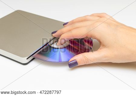 Woman Inserting A Laser Disc Into A Disk Drive. The Hand Takes The Disk Out Of The Drive. Hand Inser