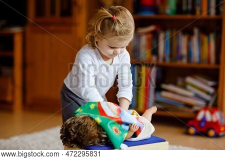 Adorable Cute Little Toddler Girl Playing With Doll. Happy Healthy Baby Child Having Fun With Role G
