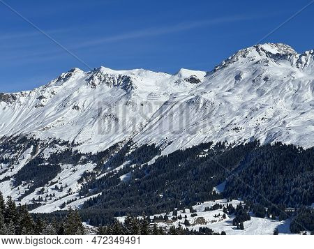 Beautiful sunlit and snow-capped alpine peaks above the Swiss tourist sports-recreational winter res