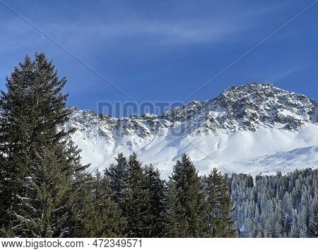 Beautiful Sunlit And Snow-capped Alpine Peaks Above The Swiss Tourist Sports-recreational Winter Res