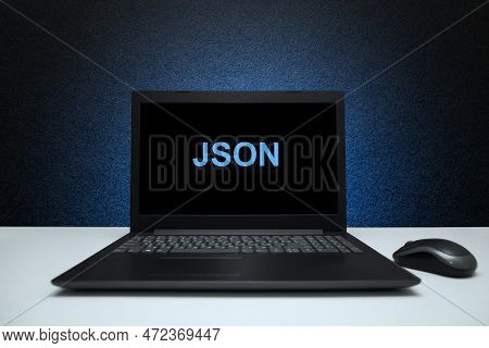 Json Text On Laptop Screen On Textured Black Background With Blue Light. Technology Concept.