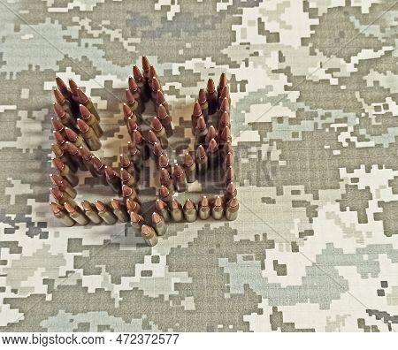 Coat Of Arms Of Ukraine Laid Out From Cartridges Against Background Of Camouflage Clothing. Cartridg