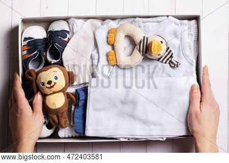 Female Hands Put Children's Clothes, Shoes And Toys Into A Box. Second Hand, Clothing Recycling Conc