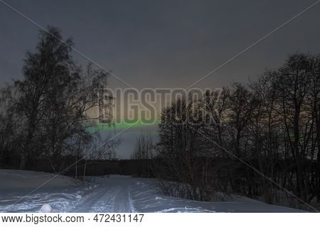 Green Streak Of Aurora Borealis Over Forest Road On February Night. Vicinities Of Vysotsk. Leningrad