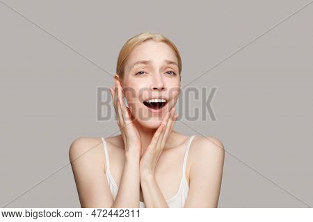 Happy Surprised Blonde Woman Isolated On Grey Background. Beauty, Cosmetics, Skincare, Glamour