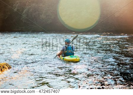 Caucasian Man Kayaking Upstream On The Whitewater Rapids, Paddling Hard On The Turbulent River