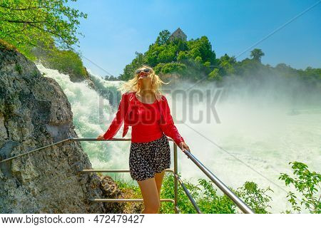 Woman At Panorama Of The Swiss Waterfall Rhine Falls In Switzerland. The Most Powerful And Big Water