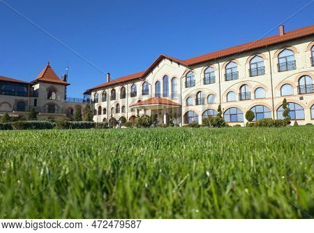 Bendery Moldova - April 22, 2021: Lawn With Green Grass And Blurred Silhouette Of A Restaurant Hotel