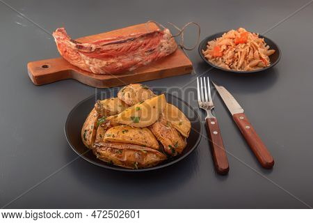 Baked Potato Wedges With Herbs And Salt In A Black Plate With A Piece Of Smoked Meat And Stewed Cabb