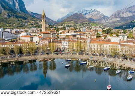 Sunny Aerial Cityscape Of Lecco Town On Spring Day. Picturesque Waterfront Of Lecco Town Located Bet