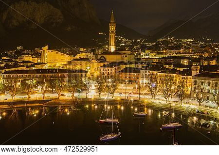 Nighttime Aerial Cityscape Of Lecco Town. Picturesque Waterfront Of Lecco Town Located Between Famou