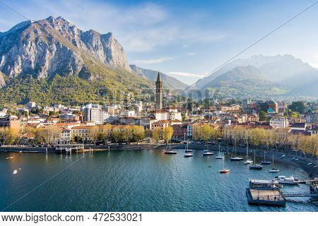 Sunny Aerial Cityscape Of Lecco Town On Spring Morning. Picturesque Waterfront Of Lecco Town Located