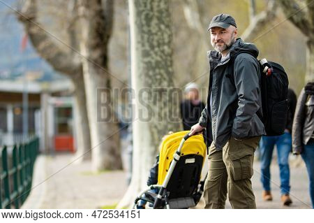 Young Father With His Toddler Son In A Stroller Having Fun In Marina Of Lecco Town. Picturesque Wate