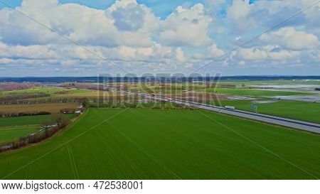 Aerial View Of A Drone On The A7 Motorway In Northern Germany Between Fields And Meadows.
