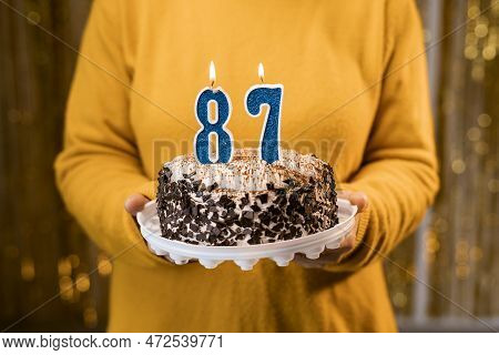 Woman Holding A Festive Cake With Number 87 Candles While Celebrating Birthday Party. Birthday Holid