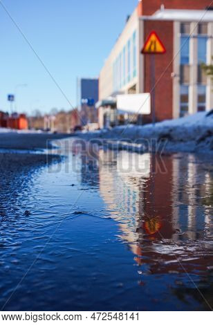 Reflection Of A Building In A Frozen Puddle
