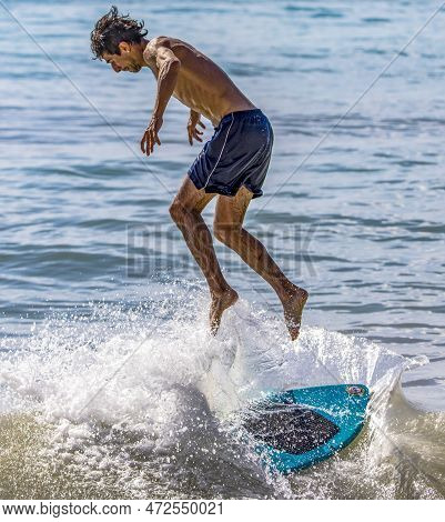 Playa Del Carmen, Mexico - March 12, 2023: Man Surfing And Jumping Over The Waves Of The Caribbean S