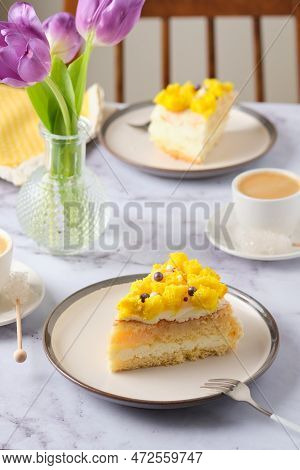 Sliced Biscuit Cake With Cream Cheese Cream, Lemon Layer And Yellow Biscuit Decor On A Ceramic Plate