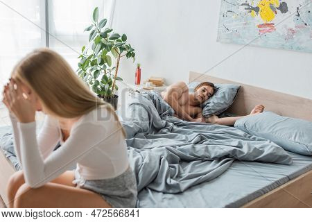 Young Shirtless Man Sleeping In Bed After One Night Stand With Woman On Blurred Foreground.