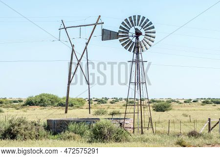 A Windmill With Dam And A Electricity Pylon Between Douglas And Prieska In The Northern Cape Provinc