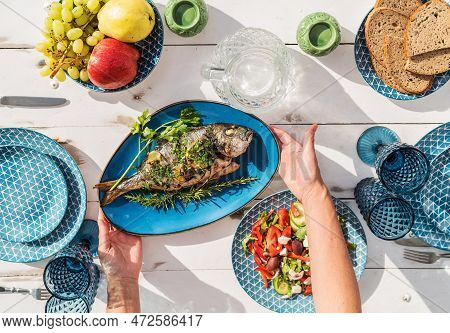 Gilt-head Bream Also Known As Orata Grilled On A Barbeque Grill Served By A Woman On A White Wooden 