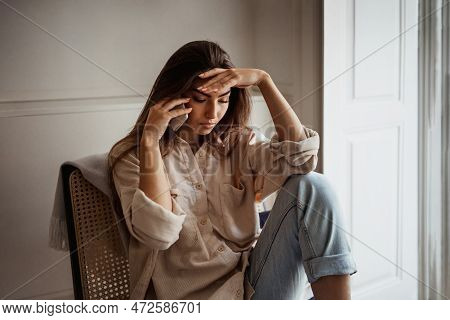 Unhappy Sad Despaired Young Asian Woman Calls By Phone, Speaks, Sits On Armchair Alone