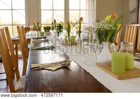 Large Wooden Table Decorated For A Dinner Party With Spring Flowers, Green Candles And Various Drink