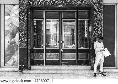 Lisbon, Portugal- October 21, 2022: Man Standing Next Aluminum Door With Geometric Details On Tiled 