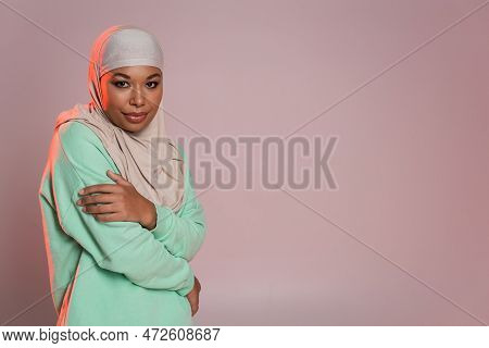 Young Multiracial Muslim Woman In Traditional Hijab And Green Long Sleeve Shirt Looking At Camera Wh