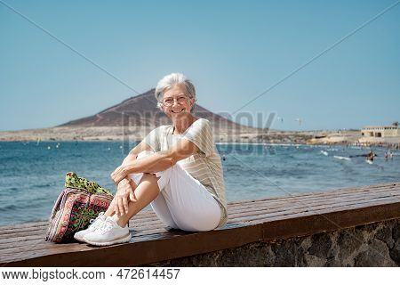 Happy Senior Woman Sitting Near The Beach Looking At Camera - Elderly Beautiful Lady Relaxes While E