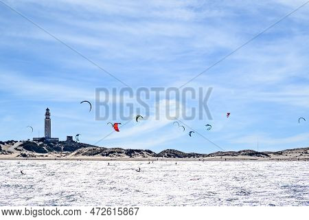 People Practicing Kitesurfing On The Beach Of Los Caños De Meja, Next To The Trafalgar Lighthouse, B