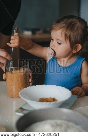 Close Up View Of Young Baby Girl Adding Flour With Spoon In A Plate Preparing Cookies Together With 