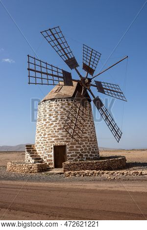 Old Traditional Windmill, Located In A Stone Desert. Blue Sky With Some White Clouds In The Winter. 