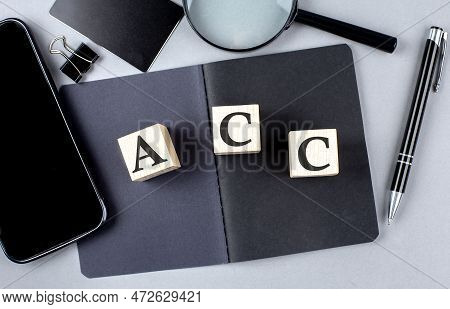 Word Acc On Wooden Block On A Black Notebook With Smartpone, Credit Card And Magnifier
