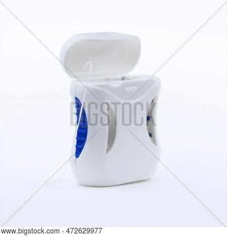 Container With Dental Floss. Dental Floss On A Blue Background. Close Up Of Young Female Hands Holdi