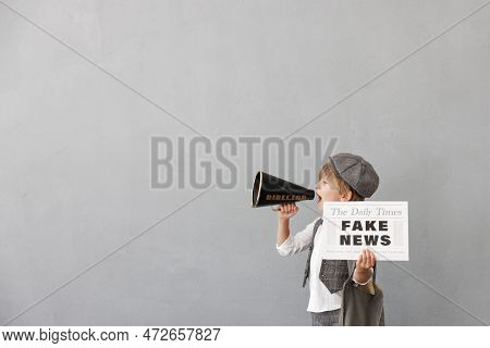 Newsboy Shouting Against Grunge Wall Background. Boy Selling Fake News