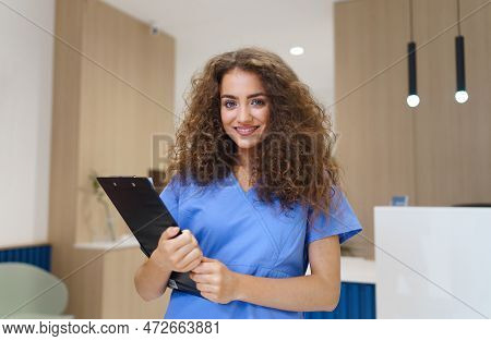 Portrait Of Dentist Nurse Posing At Reception On Private Dental Clinic.