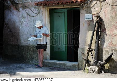 San Terenzo, Italy - May 2011: Man Reading A Newspaper By The Wall In Marina Of San Terenzo Village.
