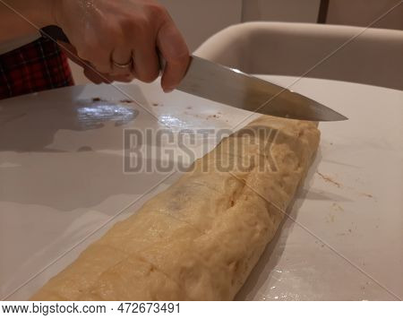 Slicing A Roll For Cinnabon Buns. Stage. A Girls Hands And A Knife. Making A Sweet Dessert Of A Cinn