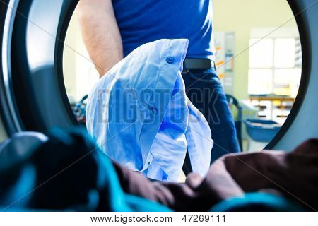 laundry in a washing machine drum, a young man takes out the coloreds