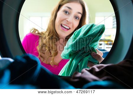 laundry in a washing machine drum, a young woman takes out the coloreds