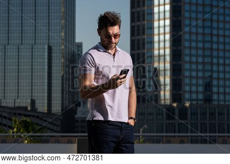 Portrait Of Handsome Man Chatting On Phone In City. Confident Man Talking On Phone In Modern Big Ame