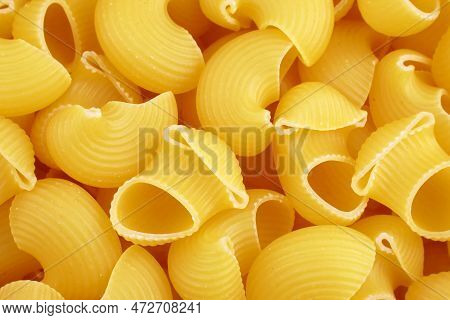 Top View Of Yellow Uncooked Pipe Rigate Snail Shape Italian Pasta Texture Close Up.