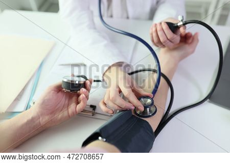 Doctor Measures Patients Blood Pressure Using Sphygmomanometer And Stethoscope. Close-up Of Process 