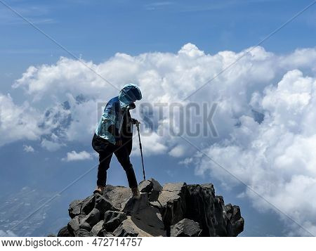 Asian Man Standing On Top Of A Nearby Mountain Looking At Mount Sindoro. West Java, Indonesia, March