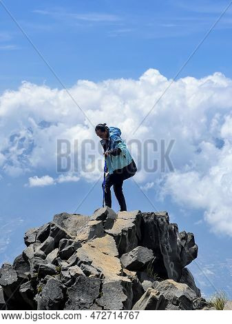 Asian Man Standing On Top Of A Nearby Mountain Looking At Mount Sindoro. West Java, Indonesia, March