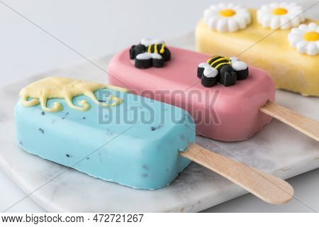 Homemade Sweet Cakesicles Decorated For Spring, Laying On A Marble Slab.