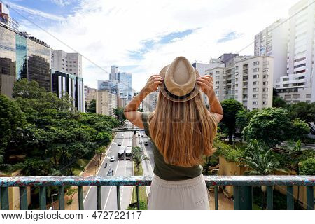 Tourism In Sao Paulo. Back View Of Beautiful Traveler Girl Holding Hat Enjoying View Of Sao Paulo Ci